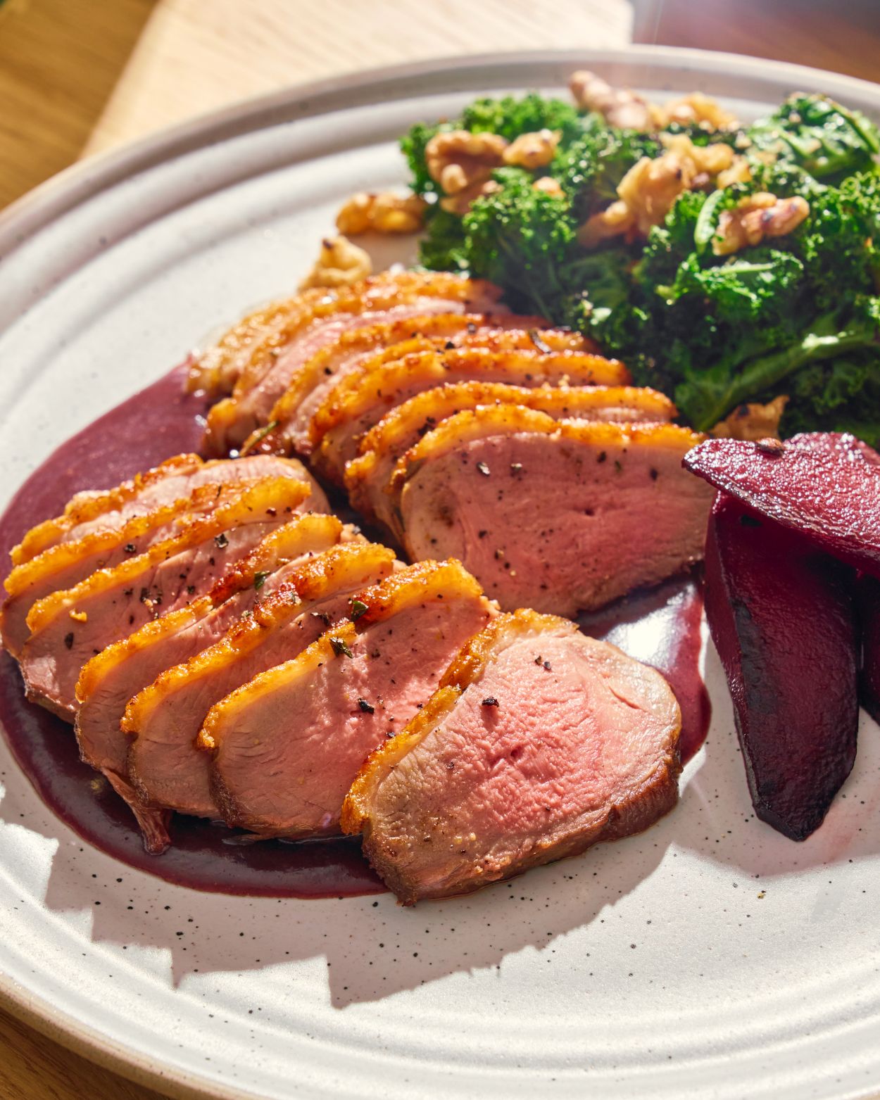 Seared duck breast with crispy skin on red wine sauce, served with kale, walnuts, and roasted beets