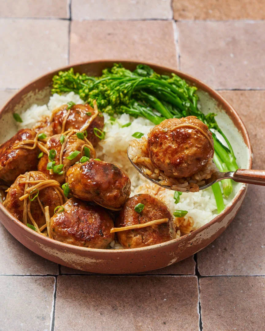 Honey soy glazed meatballs with white rice and broccolini in a rustic bowl