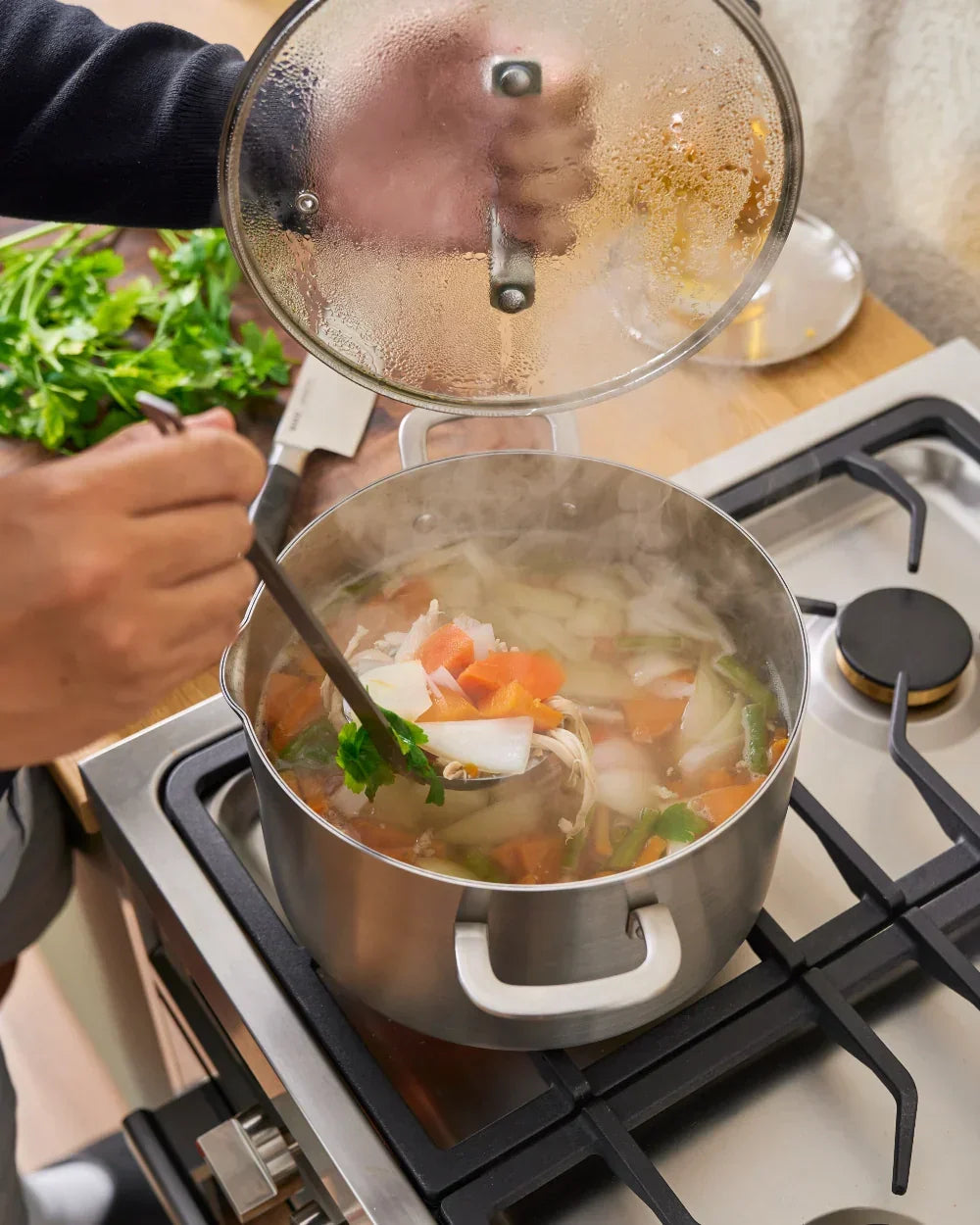 Steaming pot of homemade chicken soup with vegetables on kitchen stove