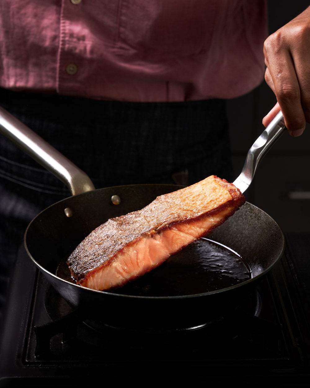 Crispy salmon fillet cooking in a nonstick mini searing pan on a stovetop