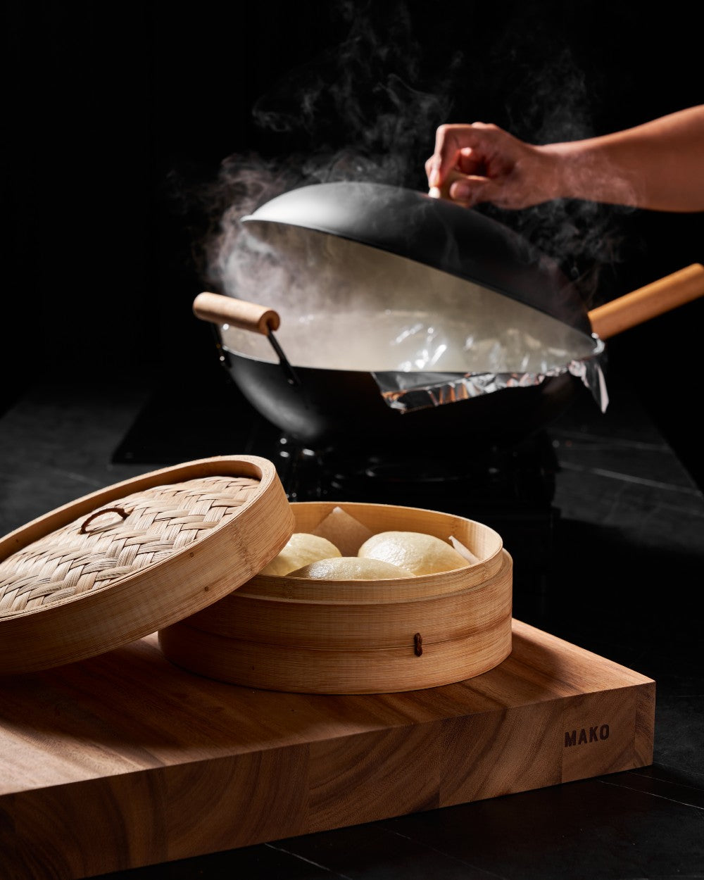 Steaming bao buns in bamboo steamer on Mako cutting board, with Mako wok in background, CookDineHost by Marion Grasby.
