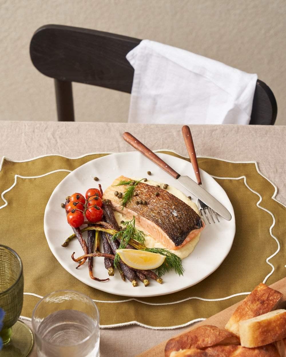 Grilled salmon with capers, roasted vegetables, lemon wedge on white Asoke ceramic plate by Marion Grasby