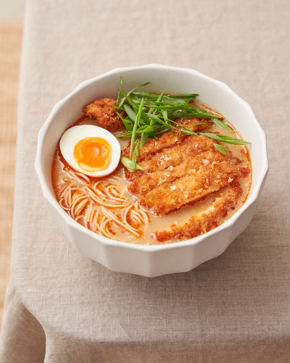 Bowl of ramen with crispy breaded chicken, soft-boiled egg, scallions, and noodles