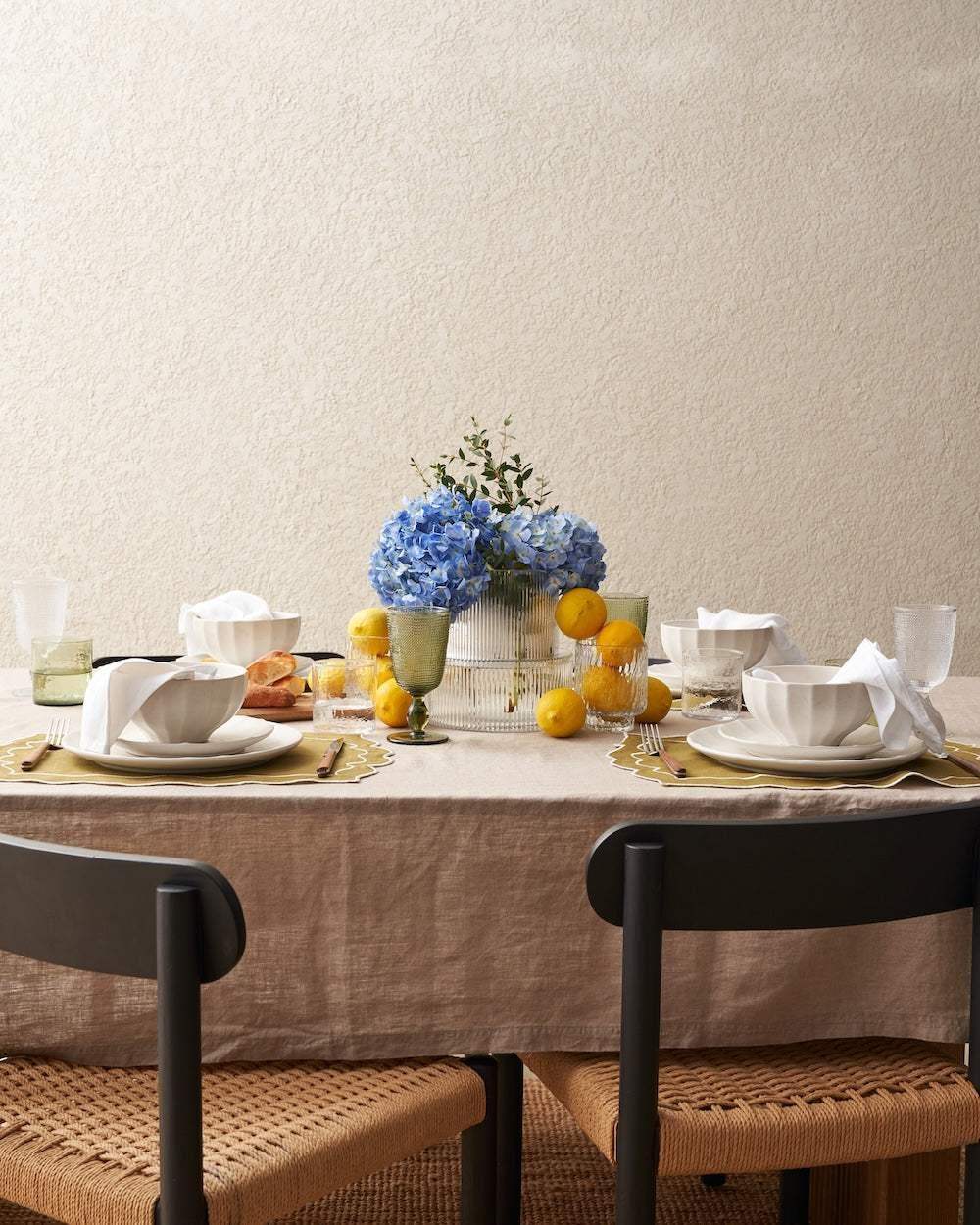 Elegant dining table set with Marion Grasby Asoke ceramic bowls, blue hydrangea centerpiece, and lemons