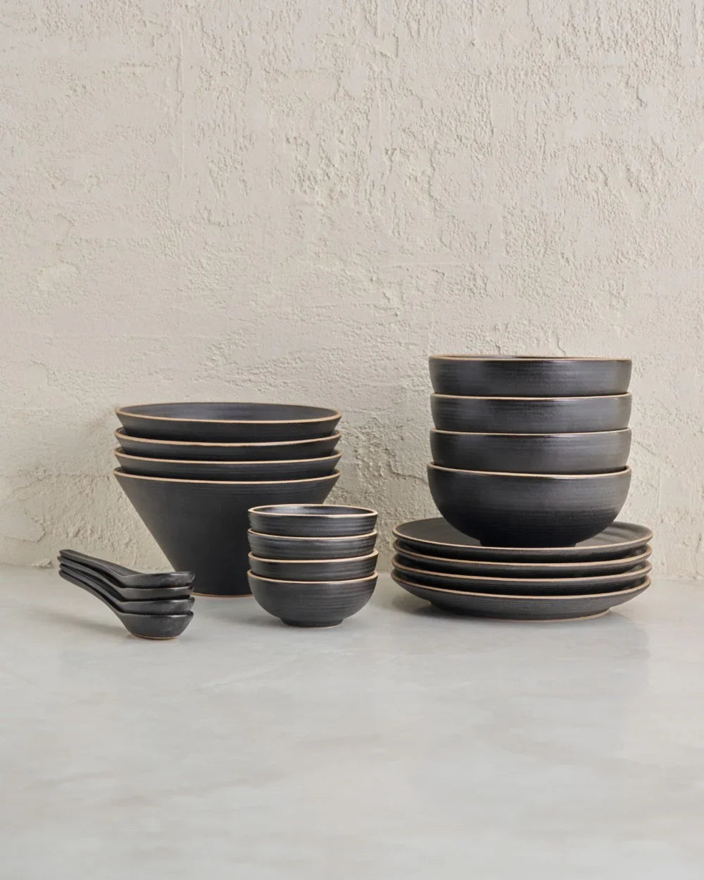 Anaya charcoal noodle lovers set featuring stacked dark matte bowls, plates, and spoons on a marble surface