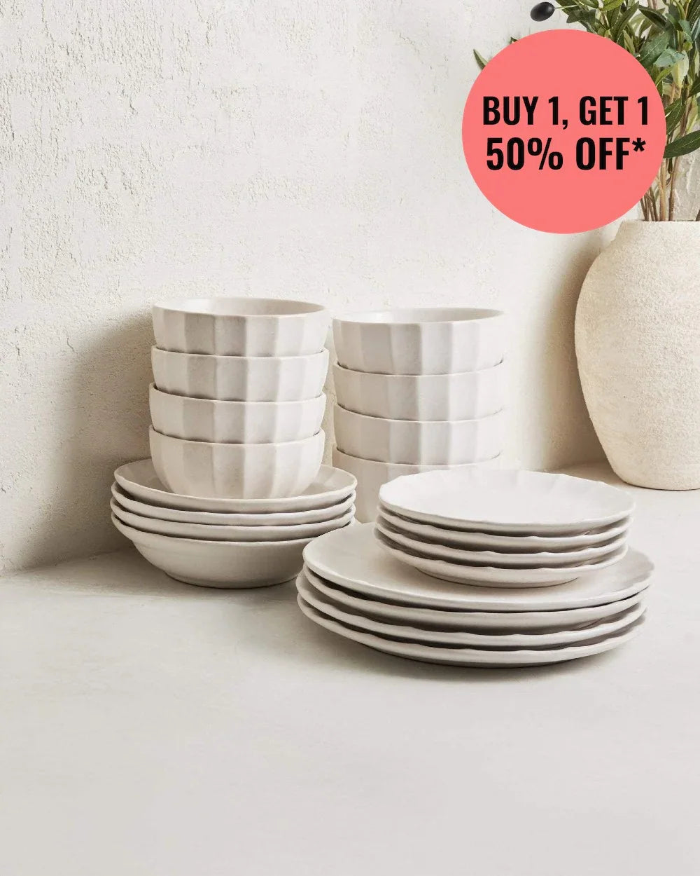 Calida Essential 20-piece white stoneware dinnerware set stacked on neutral surface with plant vase