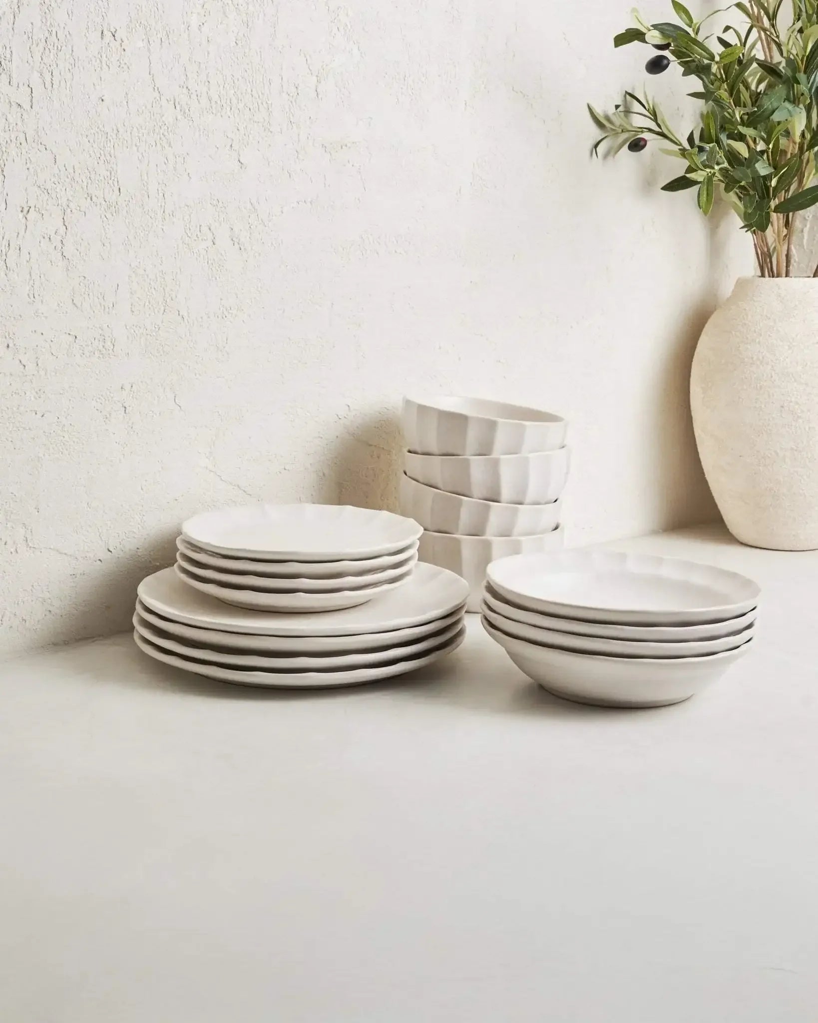 Modern white 16-piece dinnerware set with plates and bowls on a minimalist table