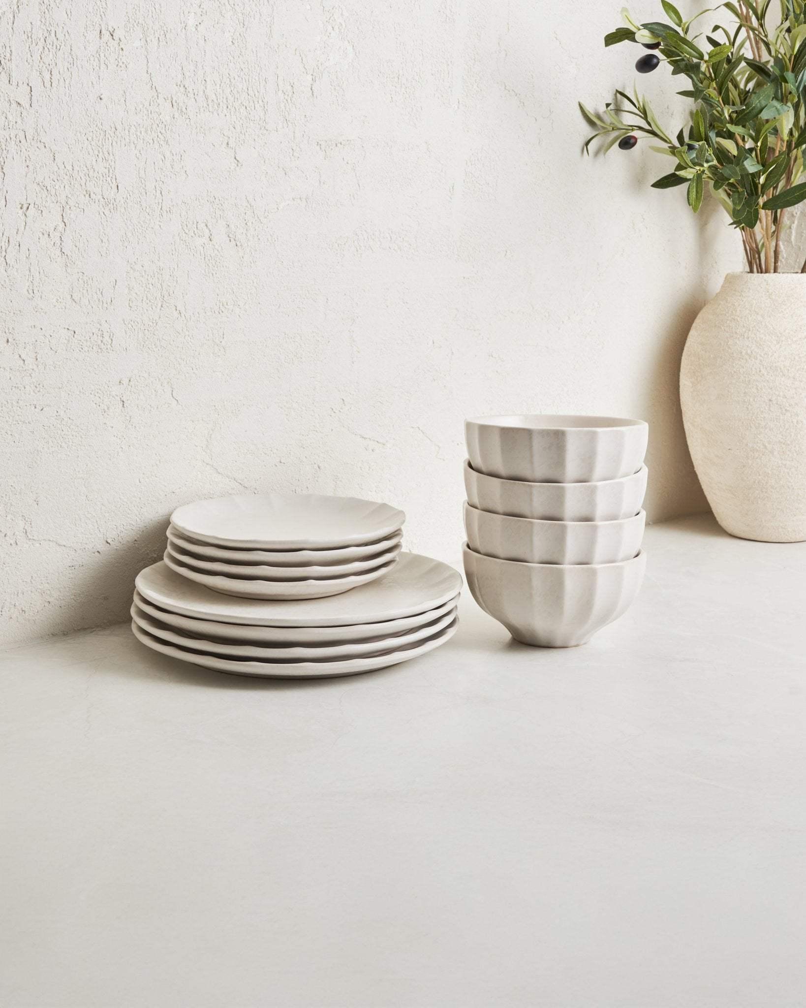 Modern white speckled dinnerware set with plates and bowls on a light tabletop, minimalist decor