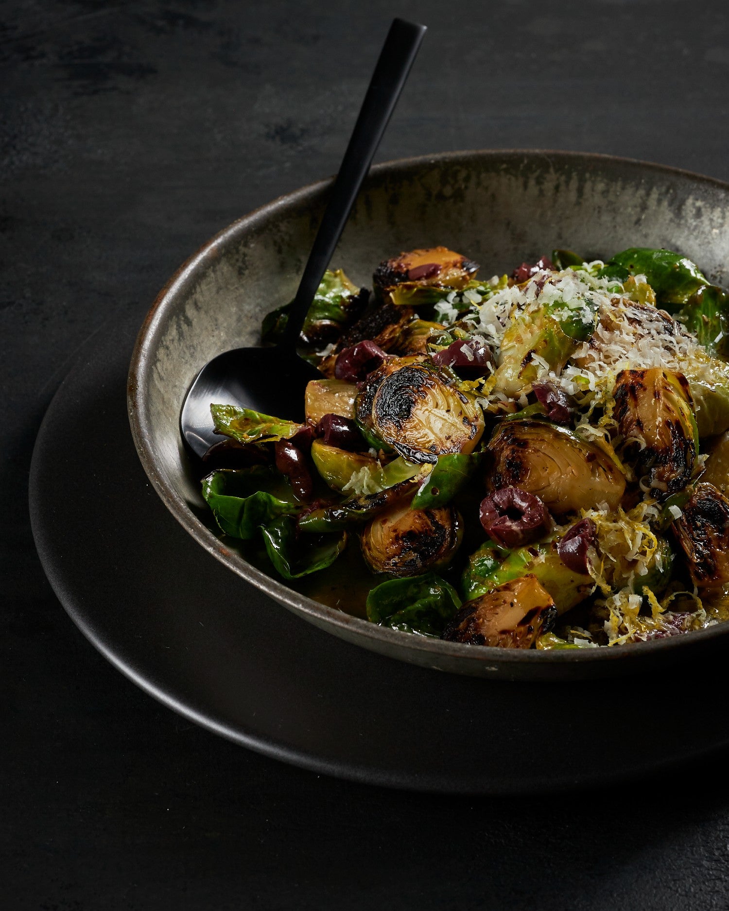 Bowl of Charred Brussel Sprouts with a spoon on a dark background