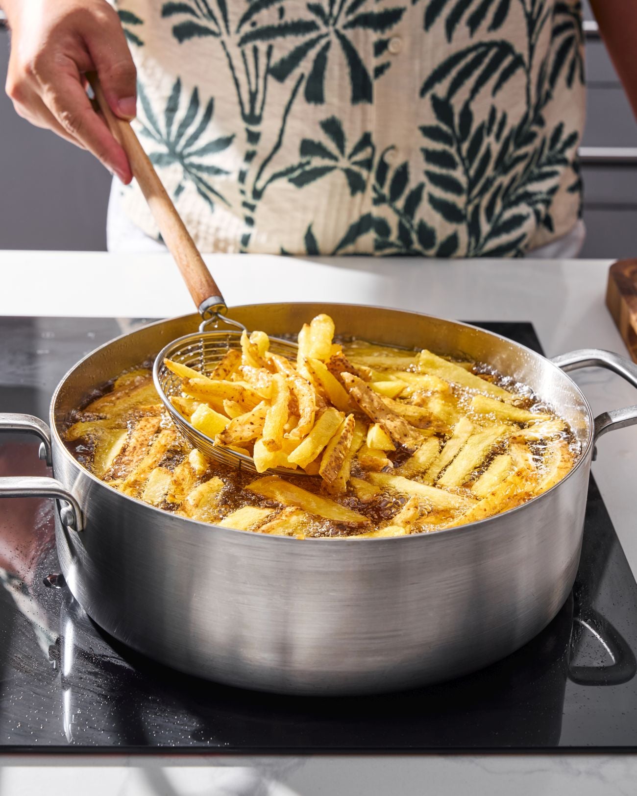 Thick-cut potatoes frying in oil in a pan