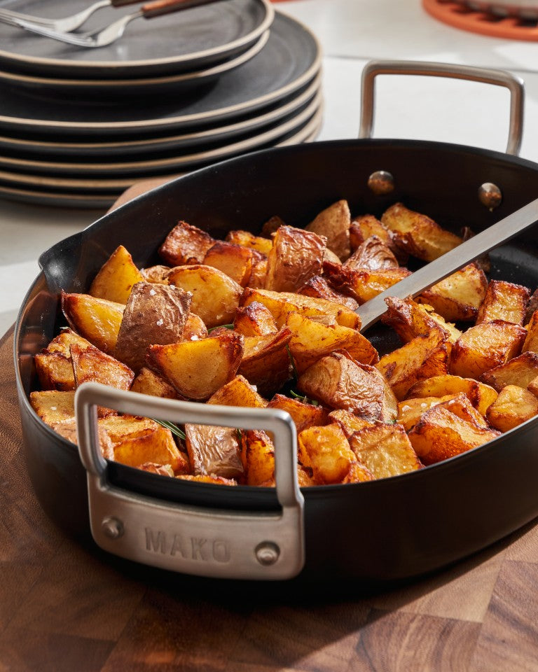 Roast potatoes in a MAKO black steel oval roaster on a wooden board