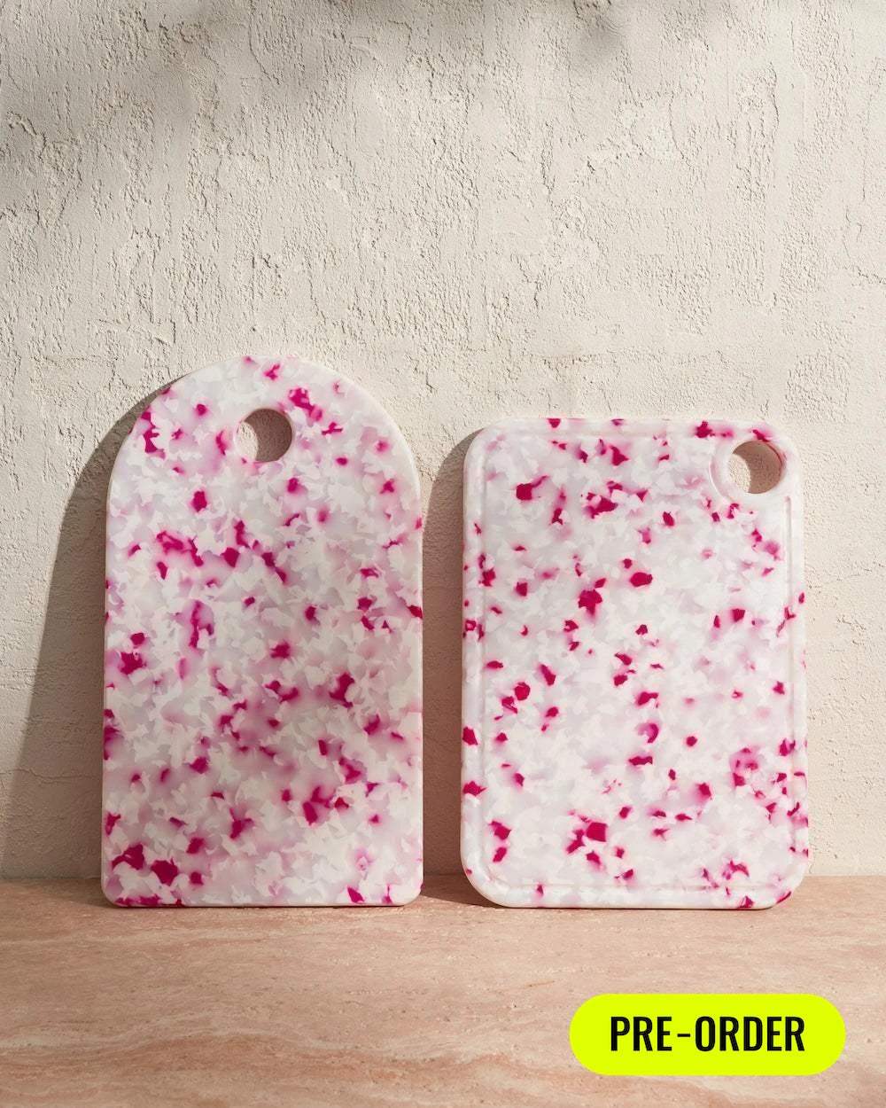 Set of two dragonfruit-pattern cutting boards with pink and white marble design on table, pre-order badge