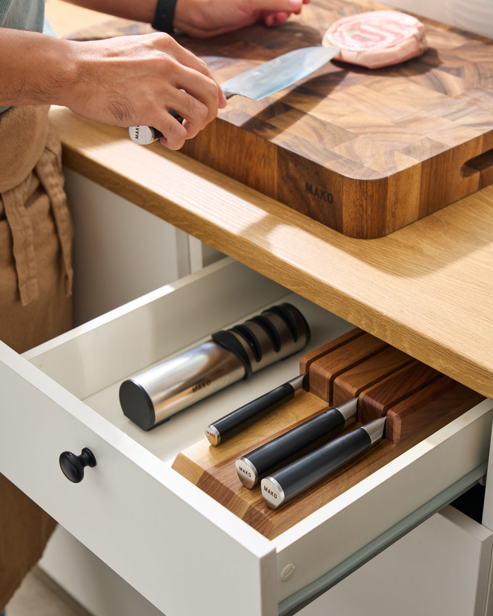 MAKO Japanese Steel Knife Set of 4 - Black Chef knife in use on benchtop with rest of the set in drawer