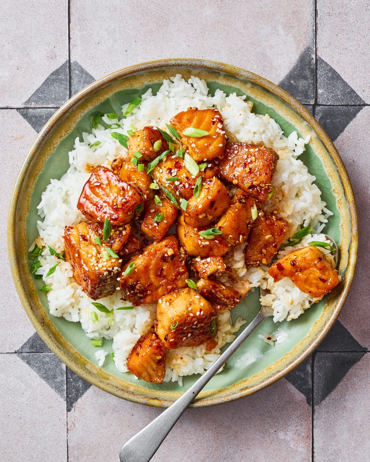 Crispy honey salmon bites with a sticky honey garlic glaze garnished with sesame seeds and spring onion