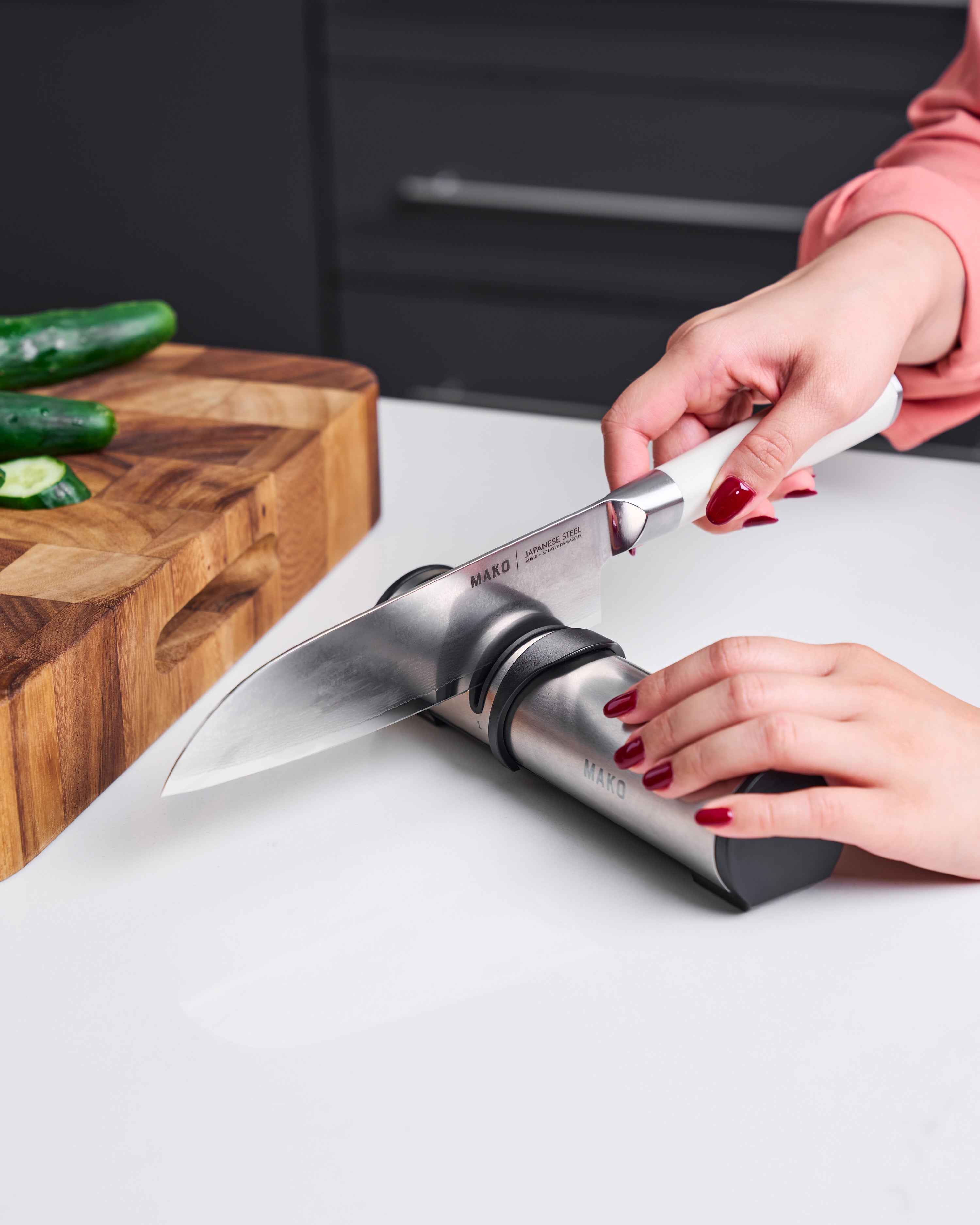 Sharpening a stainless steel kitchen knife with a manual sharpener on a countertop