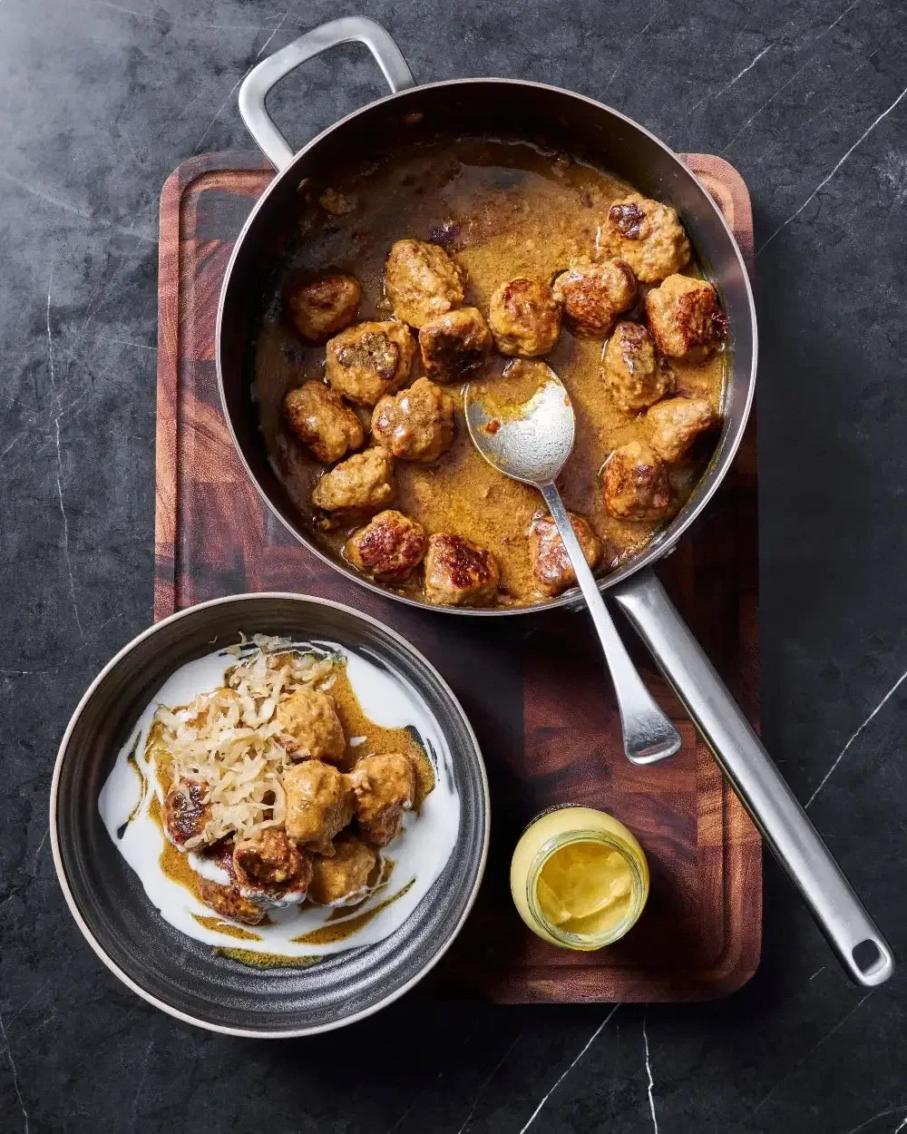 Sauté pan with cooked meatballs in sauce, served with shredded cabbage on a plate