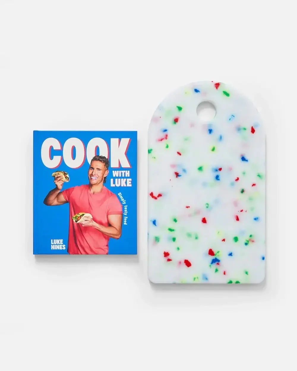 Cookbook with blue cover next to white cutting board with colorful sprinkle pattern