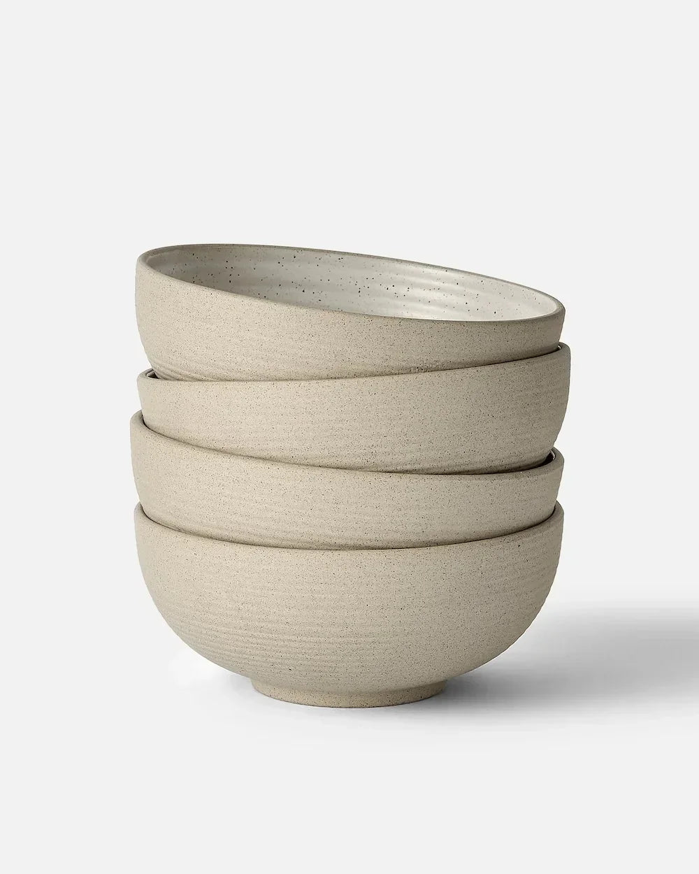 Stack of four beige speckled ceramic bowls with textured matte finish, minimalist design