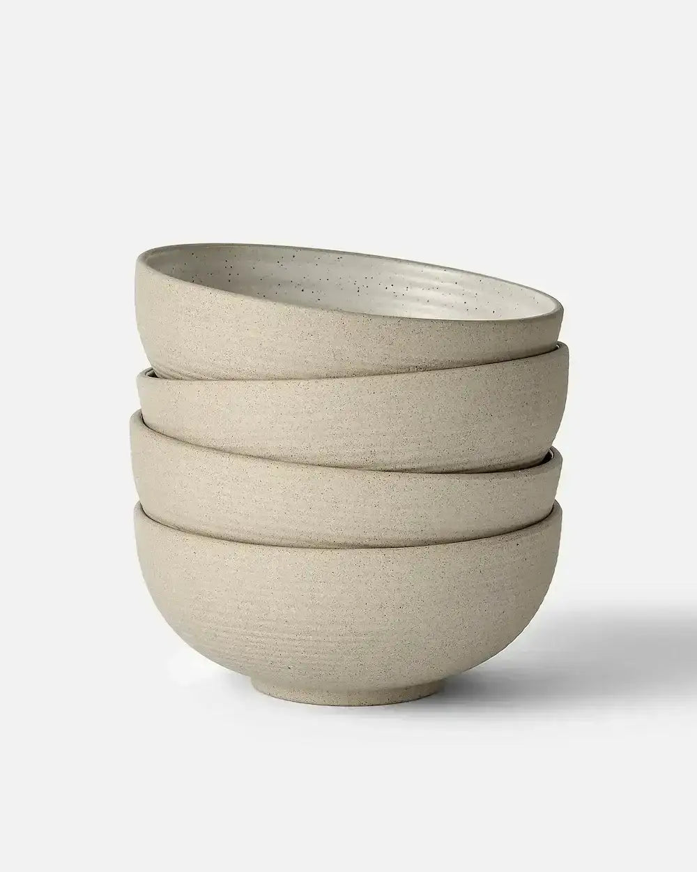 Stack of four beige speckled ceramic cereal bowls with uneven rims, minimalist design by Marion Grasby
