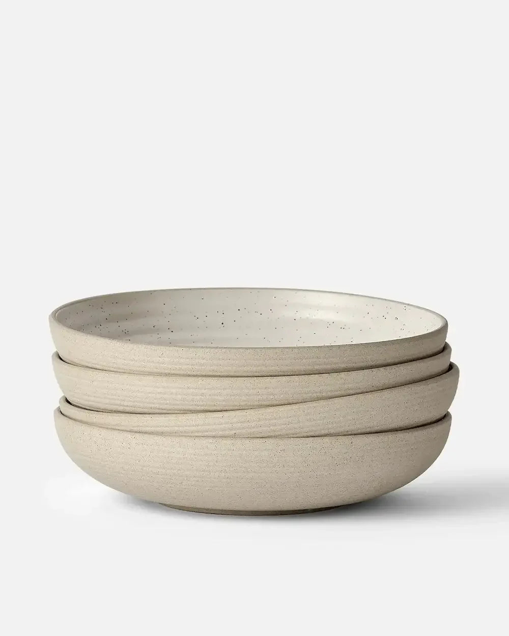Set of four wide stoneware bowls with a speckled beige finish, stacked on white background.