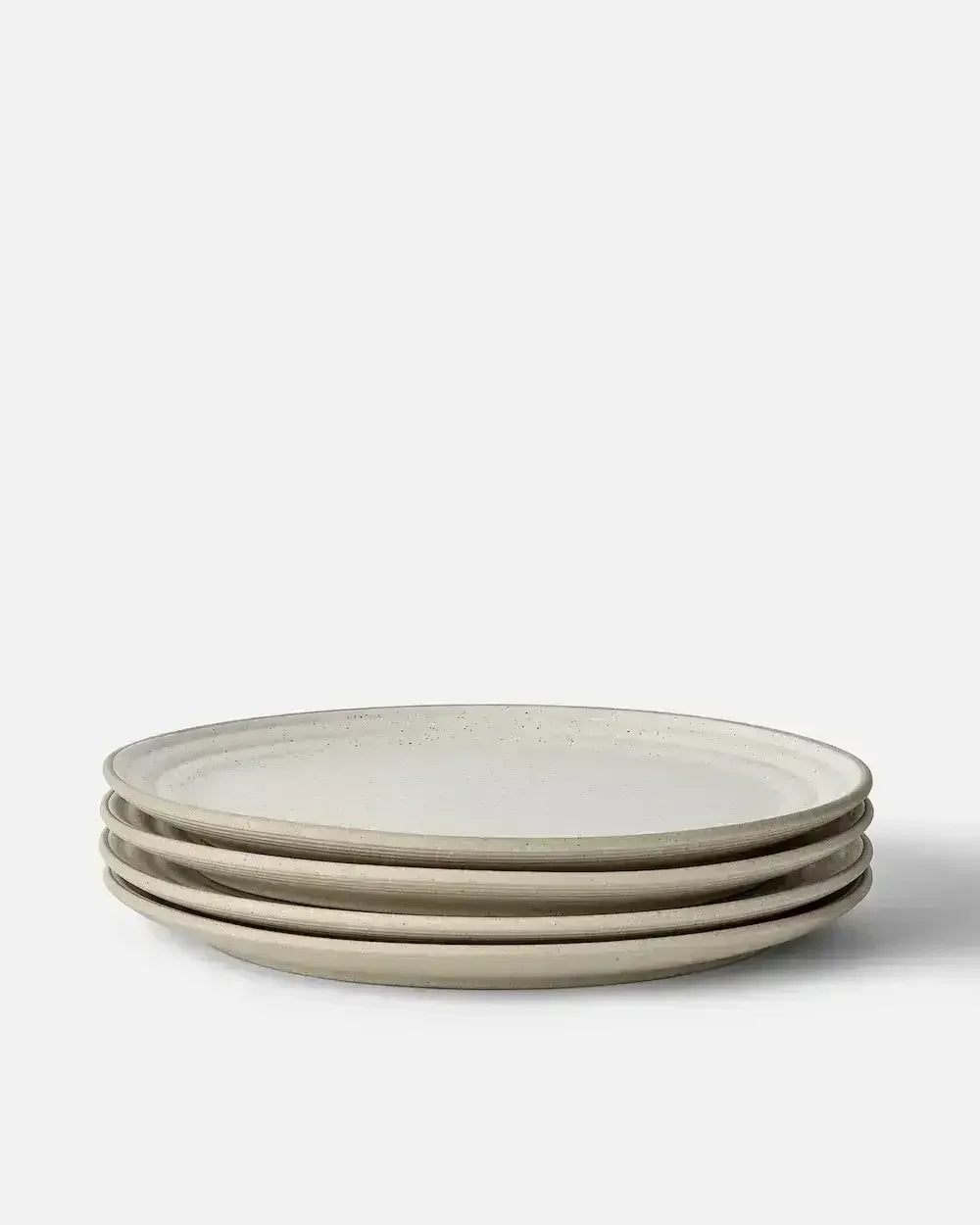 Set of four speckled stoneware dinner plates stacked on a white background