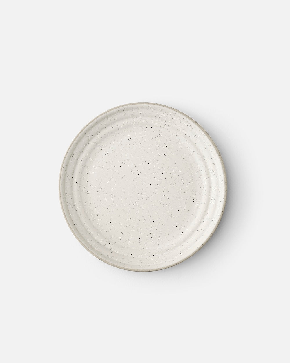 Ceramic side plate with speckled white glaze, minimalist round dinnerware on white background