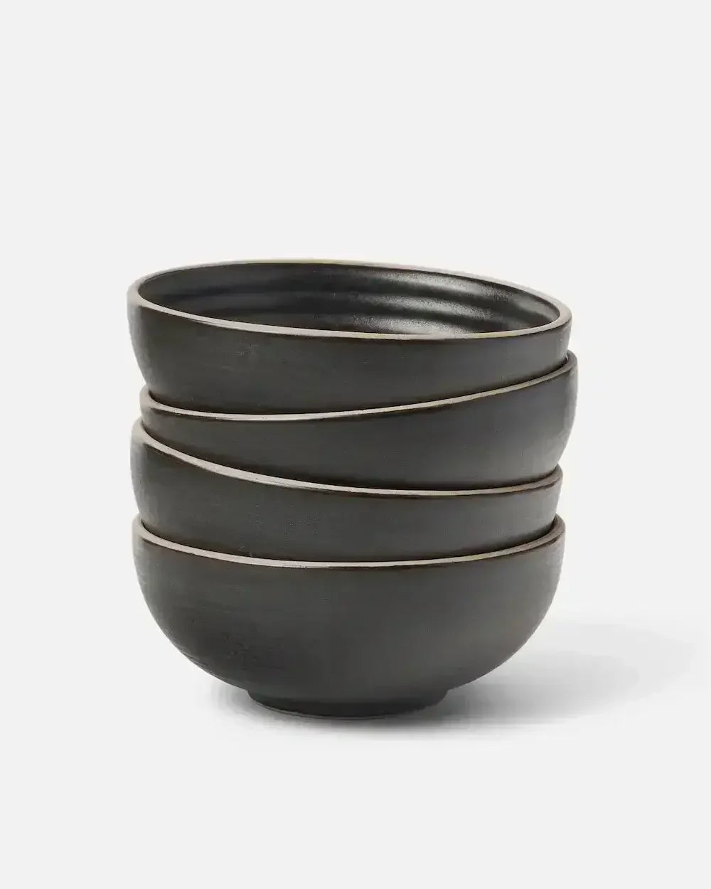 Stack of four charcoal ceramic cereal bowls with matte finish on white background