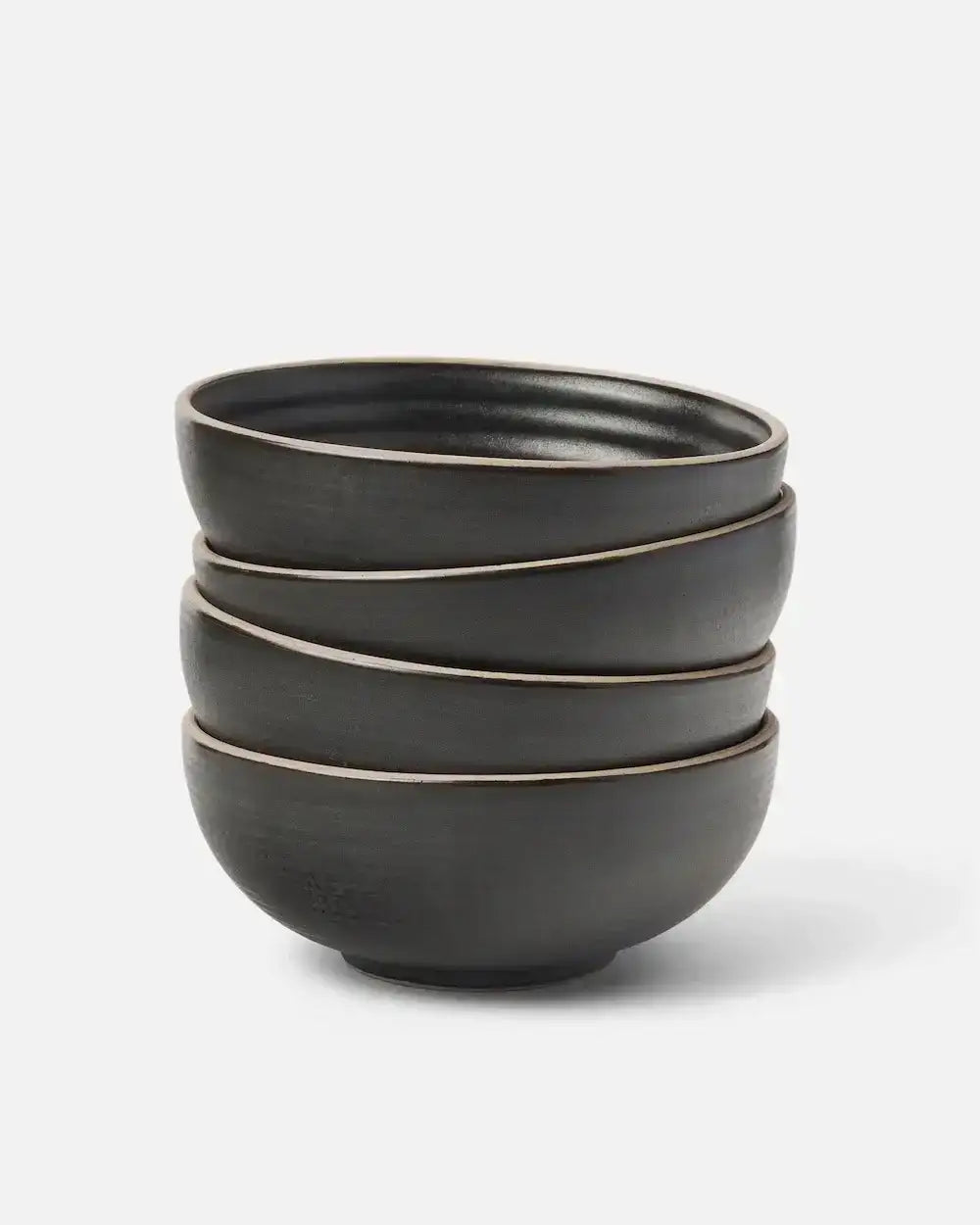 Stack of four black Asoke ceramic cereal bowls by Marion Grasby on white background