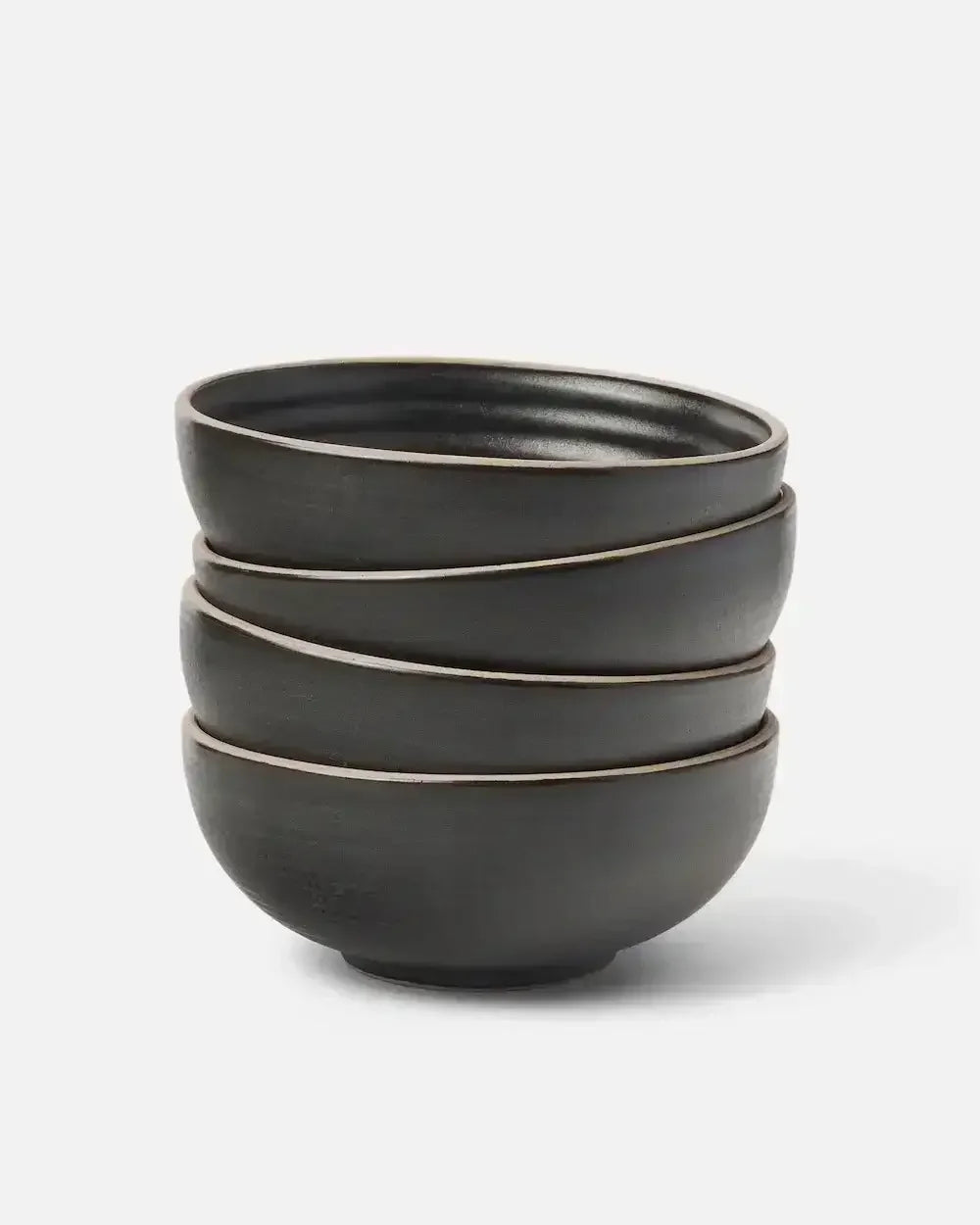 Stacked set of four matte charcoal ceramic cereal bowls on white background
