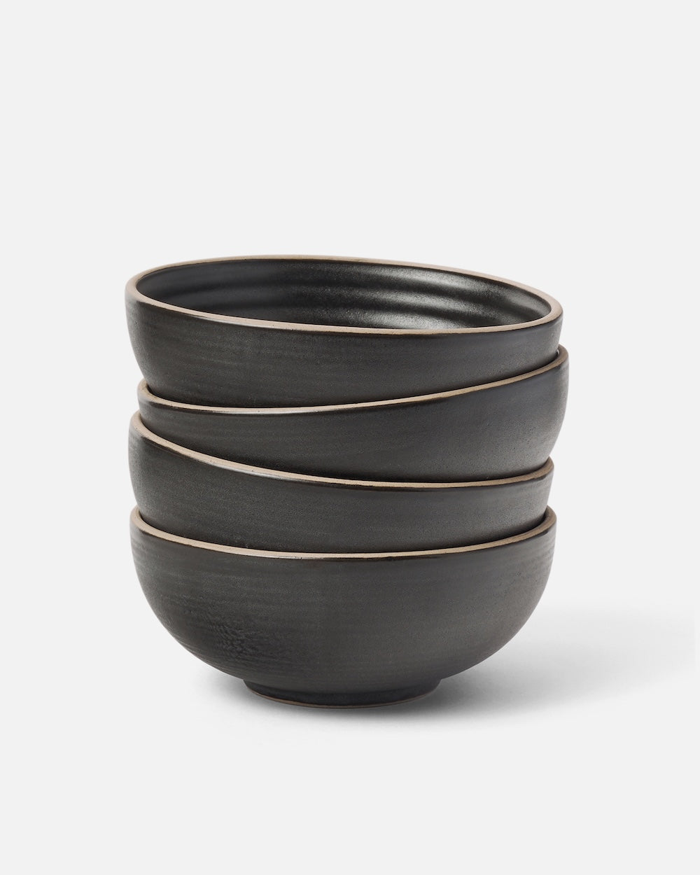 Stacked set of four matte charcoal ceramic cereal bowls on white background