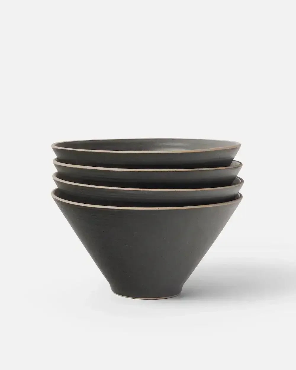 Stacked set of four matte charcoal ceramic noodle bowls on white background