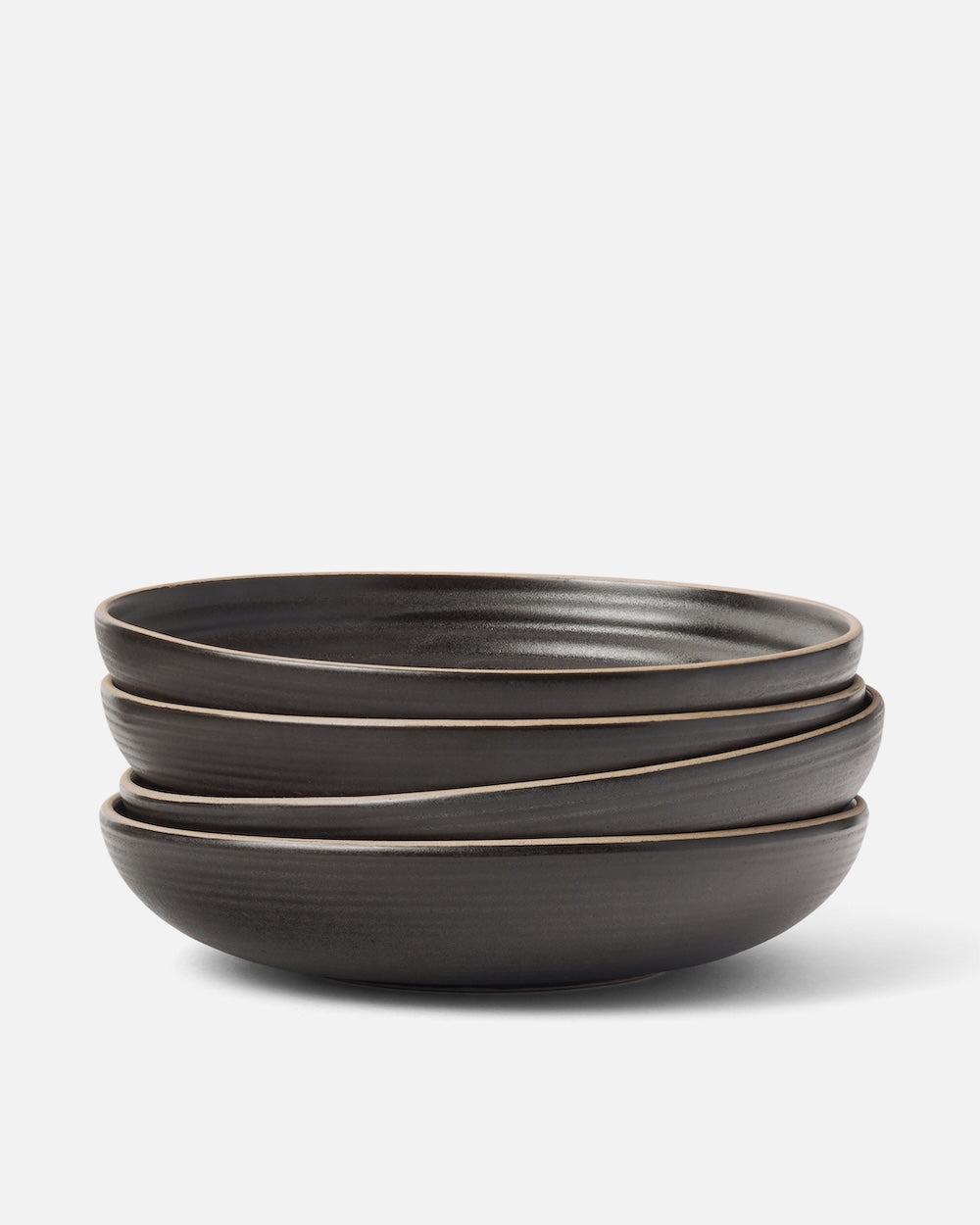 Stacked set of four charcoal stoneware wide bowls on a white background