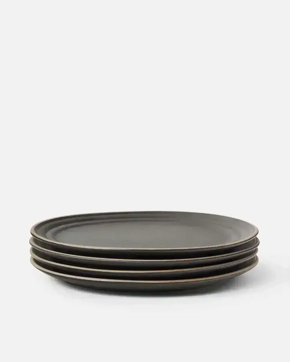 Stack of four matte charcoal ceramic dinner plates on a plain white background