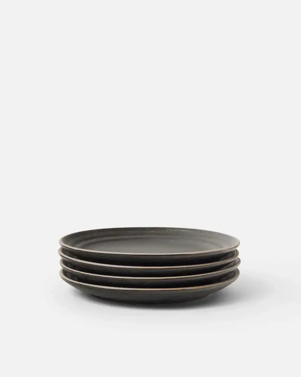 Stack of four charcoal side plates from Marion Grasby's Asoke collection on a white background