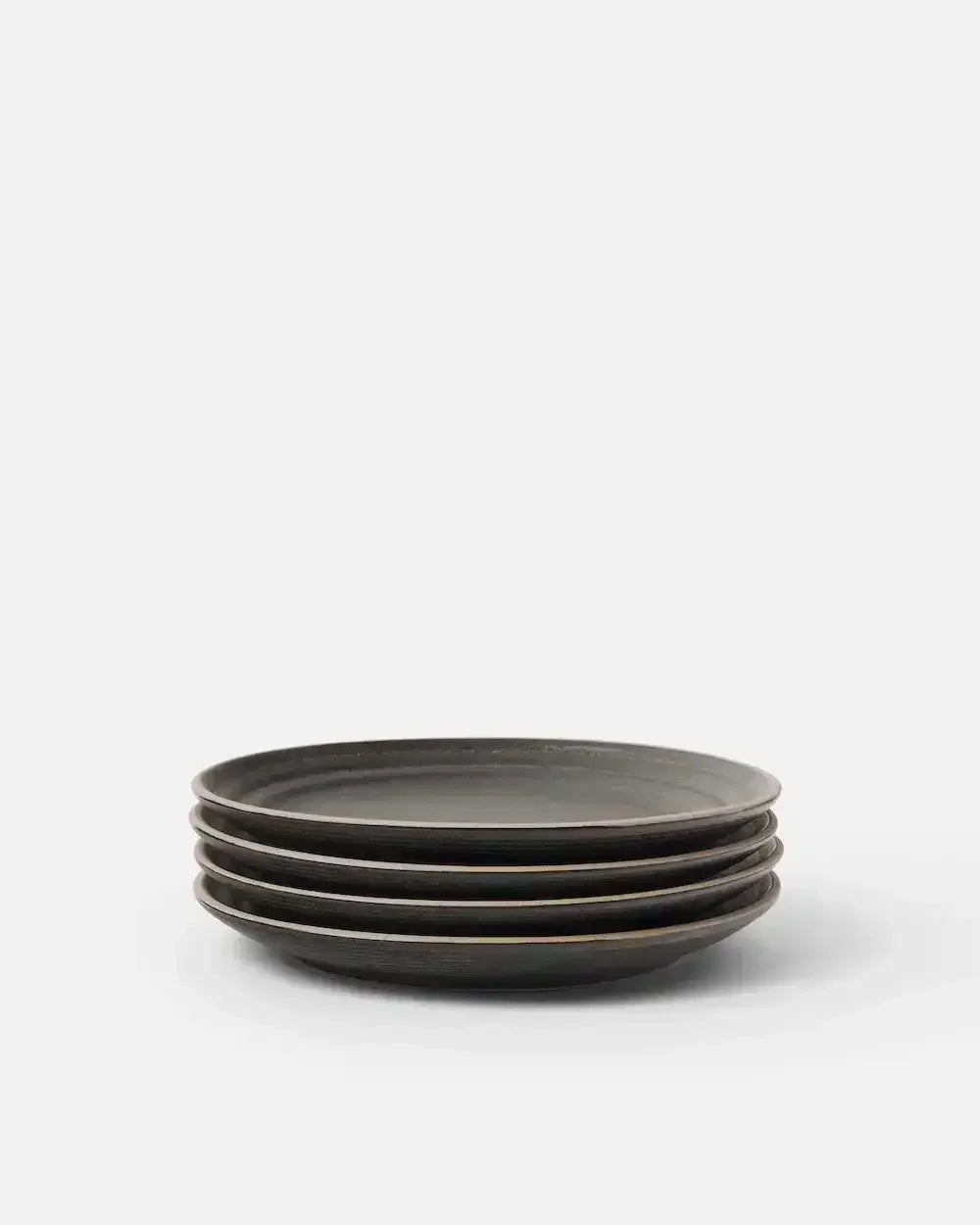 Set of four charcoal ceramic side plates stacked on a white background