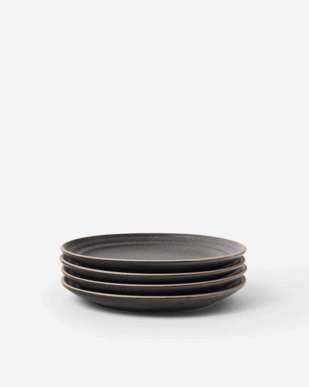 Stack of four charcoal ceramic side plates on white background