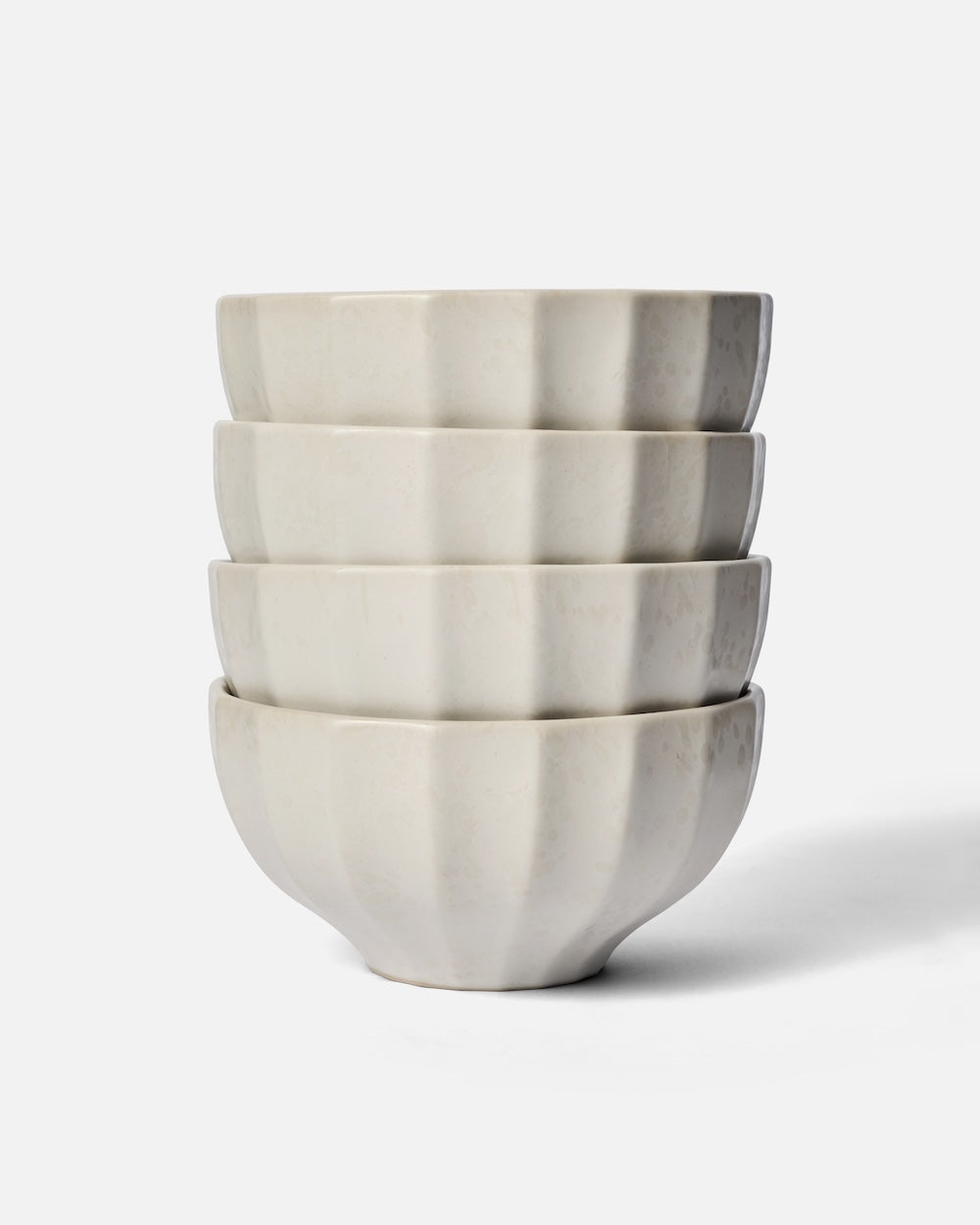 Stack of four white fluted ceramic cereal bowls on a plain background