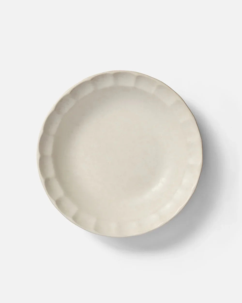 Cream-colored ceramic pasta bowl with scalloped edge on white background by Marion Grasby