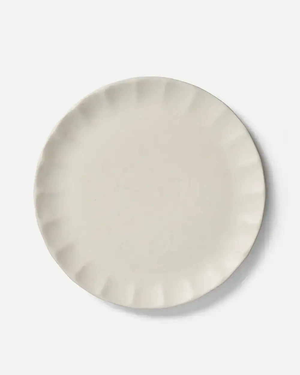 Cream-colored ceramic dinner plate with scalloped edges, minimalist design by Marion Grasby