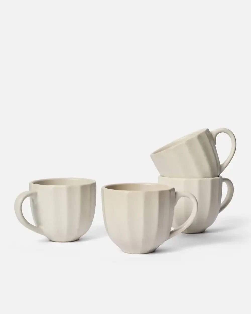 Set of four cream-colored fluted ceramic mugs with handles, minimalist design, on white background