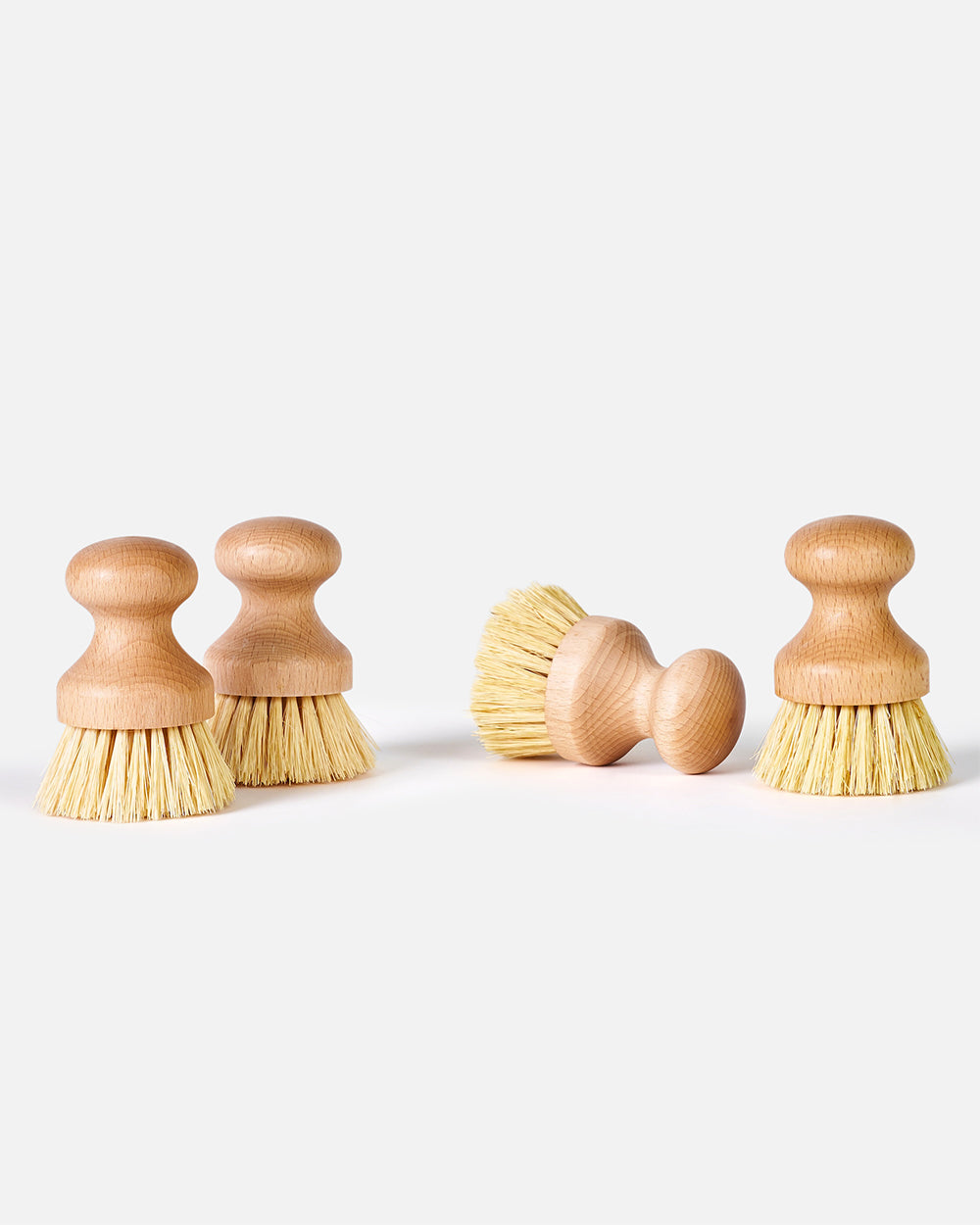 Set of four round wooden dish scrub brushes with natural bristles on a white background.