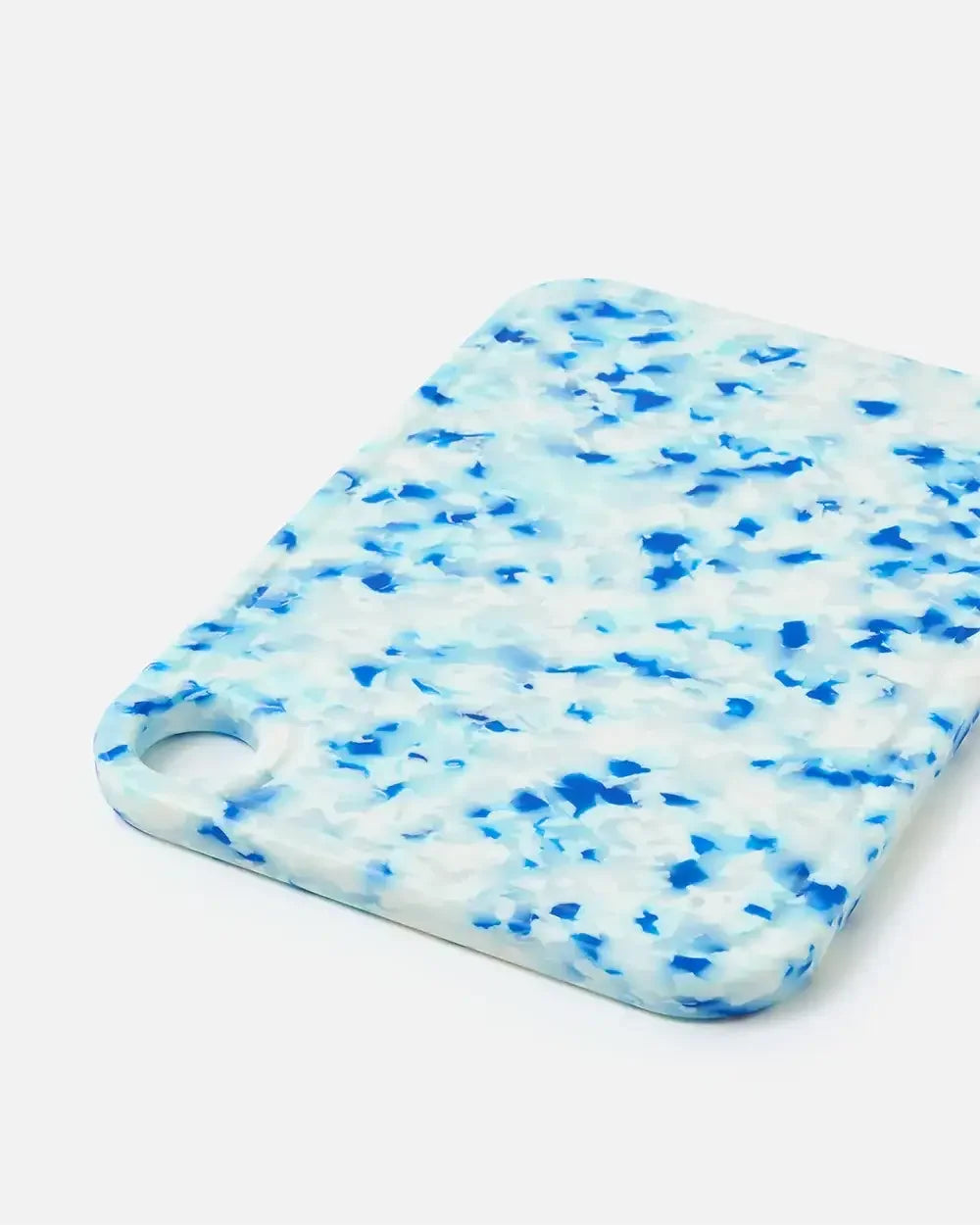 Rectangular blue and white terrazzo cutting board with rounded edges and handle hole