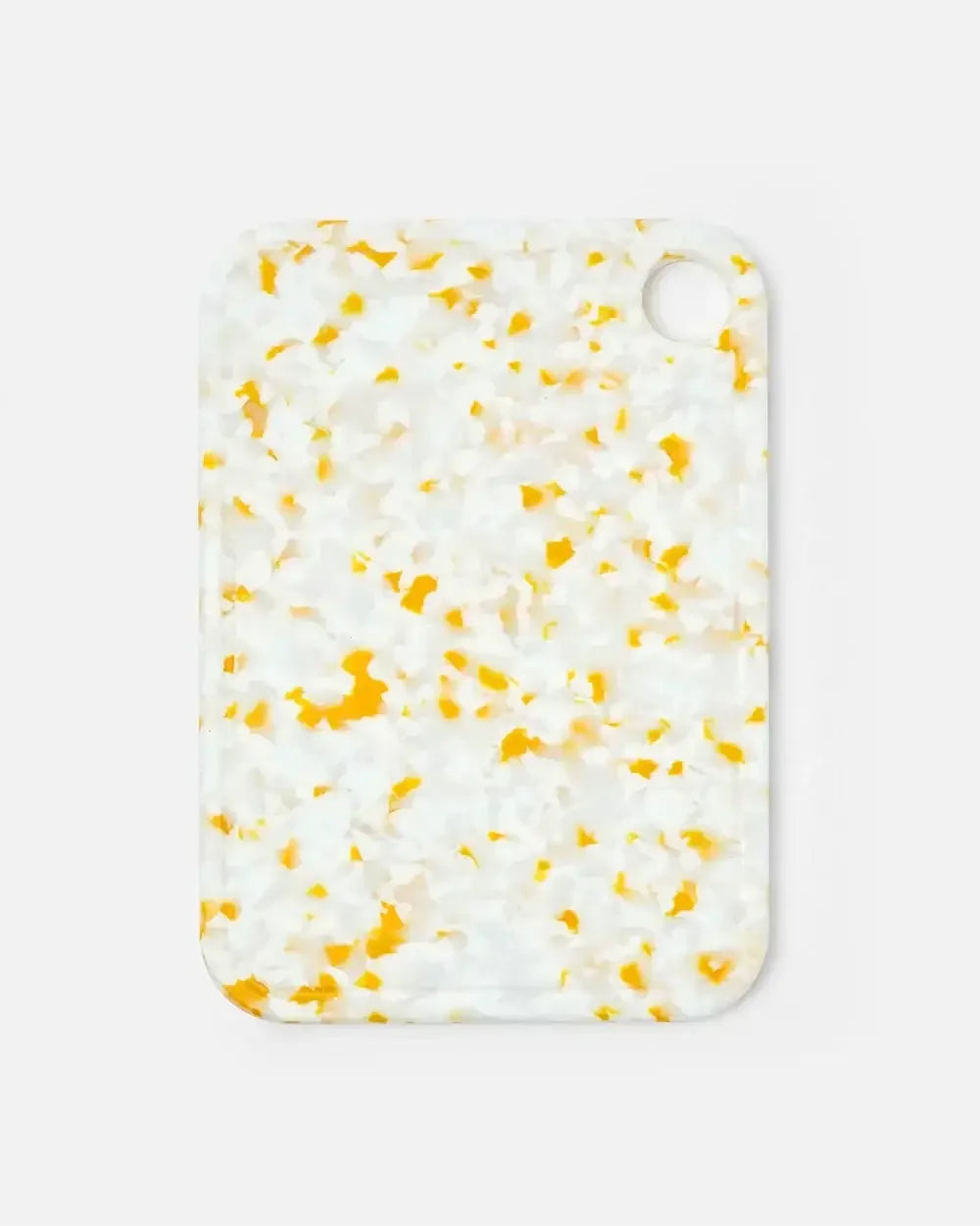 Small rectangular cutting board with yellow and white terrazzo pattern and corner hole