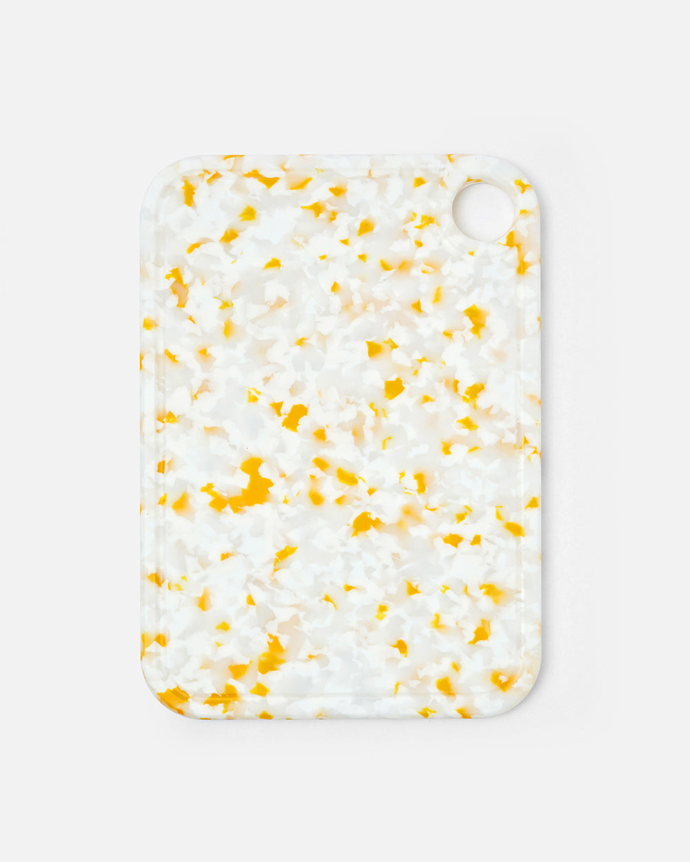Small rectangular cutting board with yellow and white terrazzo pattern and corner hole