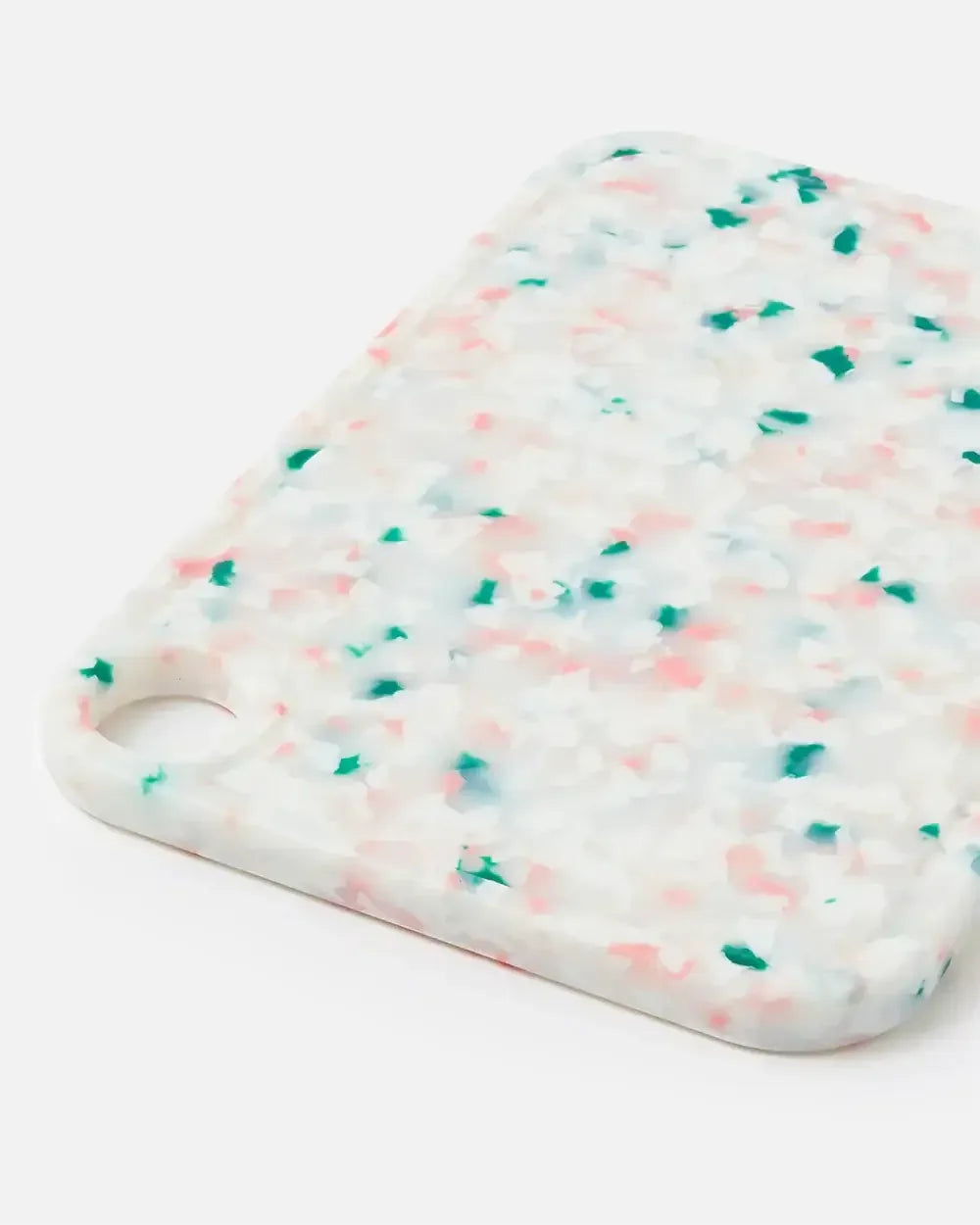Colorful speckled cutting board with pink and green terrazzo pattern on white background