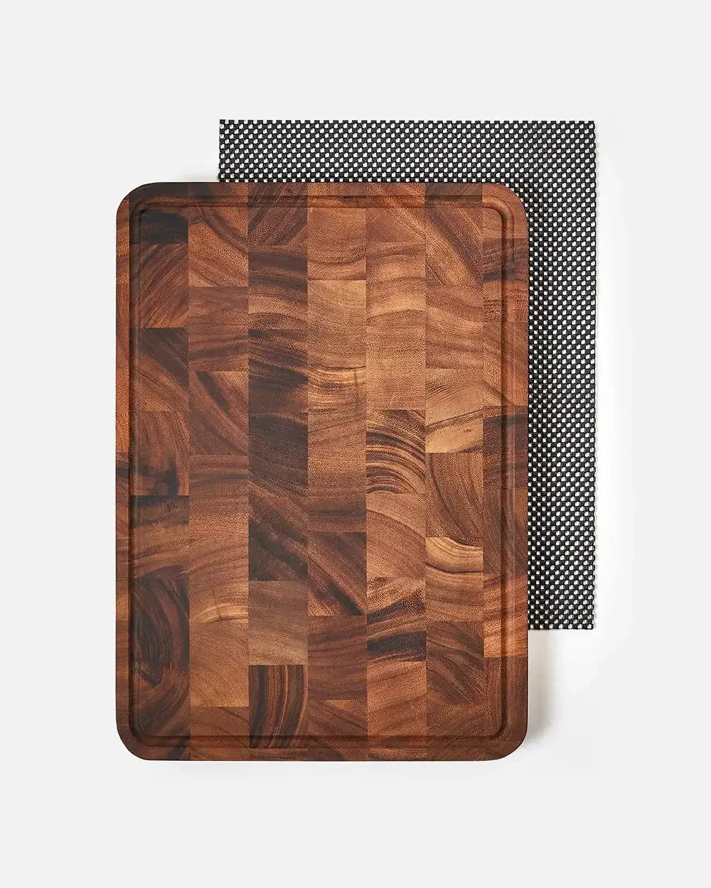 Rectangular wood chopping board with juice groove on white background, non-slip mat underneath