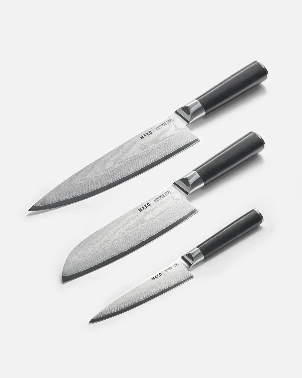 Set of three Mako Japanese steel kitchen knives with black handles on white background