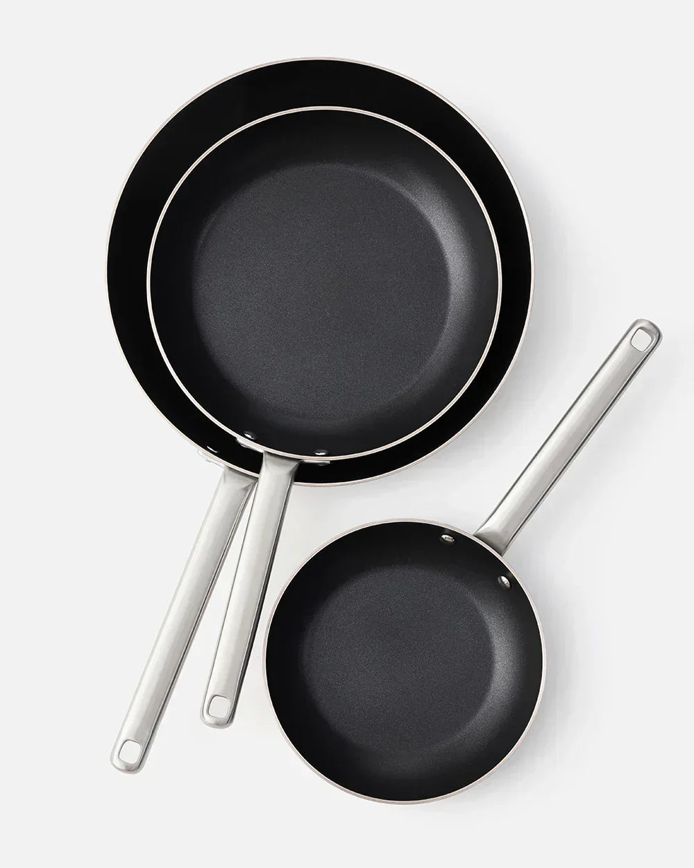 Set of three black nonstick frying pans with stainless steel handles on white background