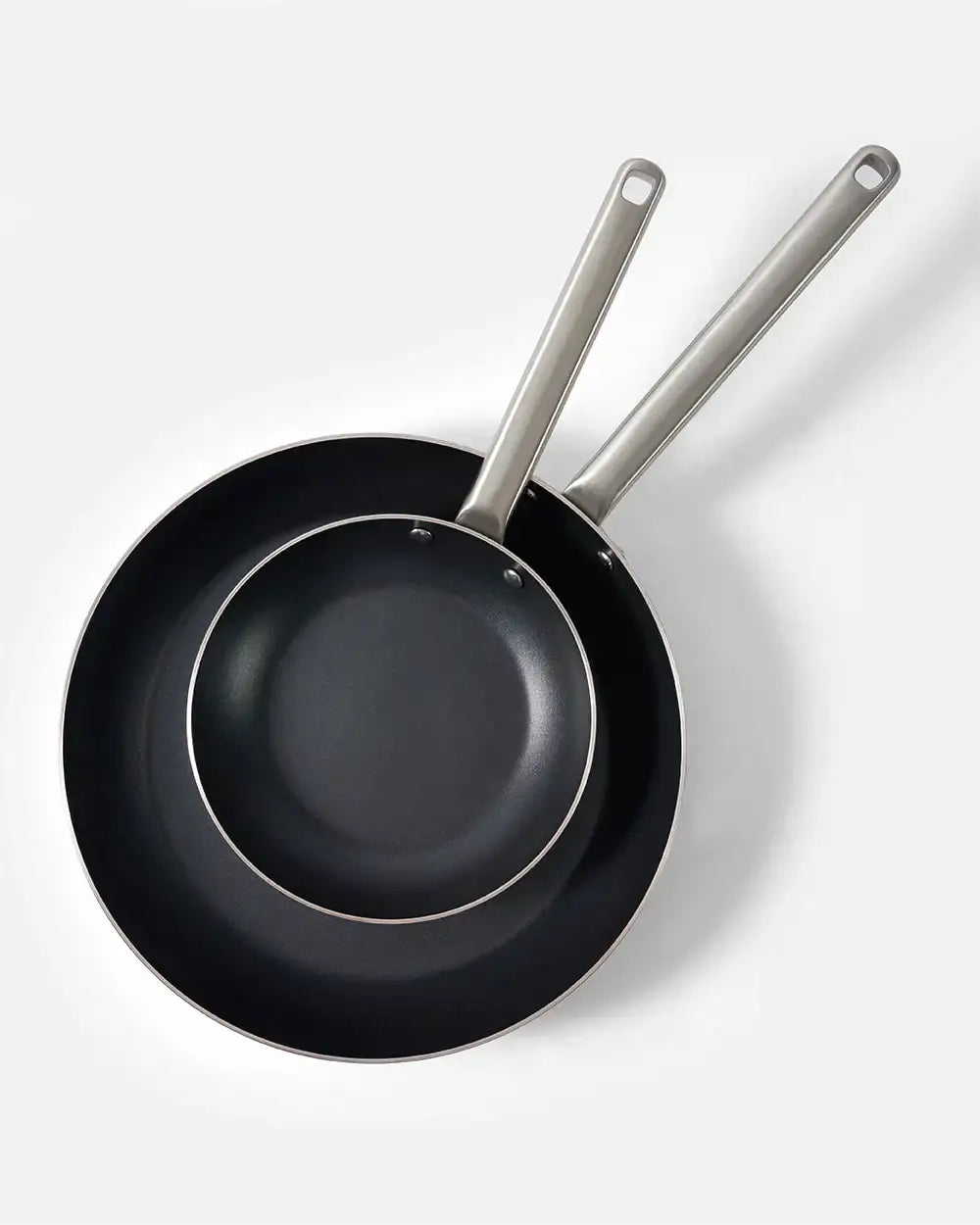 Two black non-stick frying pans with metal handles nested on a white background, Mako by Marion Grasby