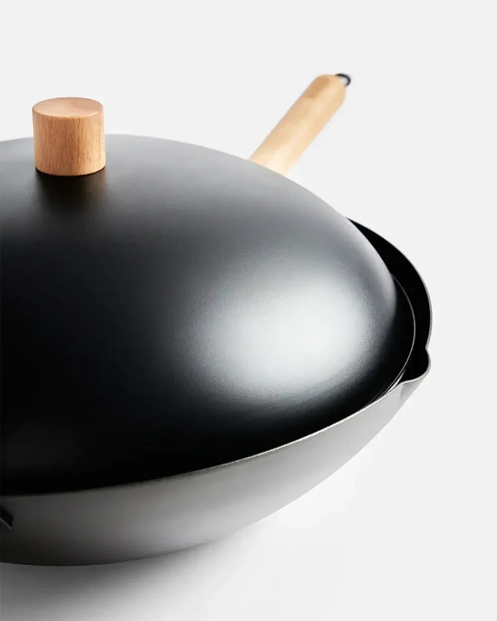 Black nonstick wok with wooden handle and lid on white background